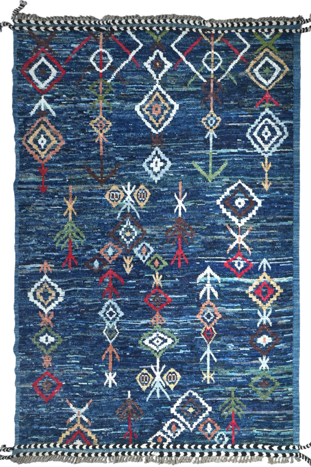 moroccan 12 x 9 rug blue woven rug featuring colorful geometric patterns, including diamonds and arrows, arranged in vertical lines. It has braided black-and-white tassels, showcasing a traditional area rug