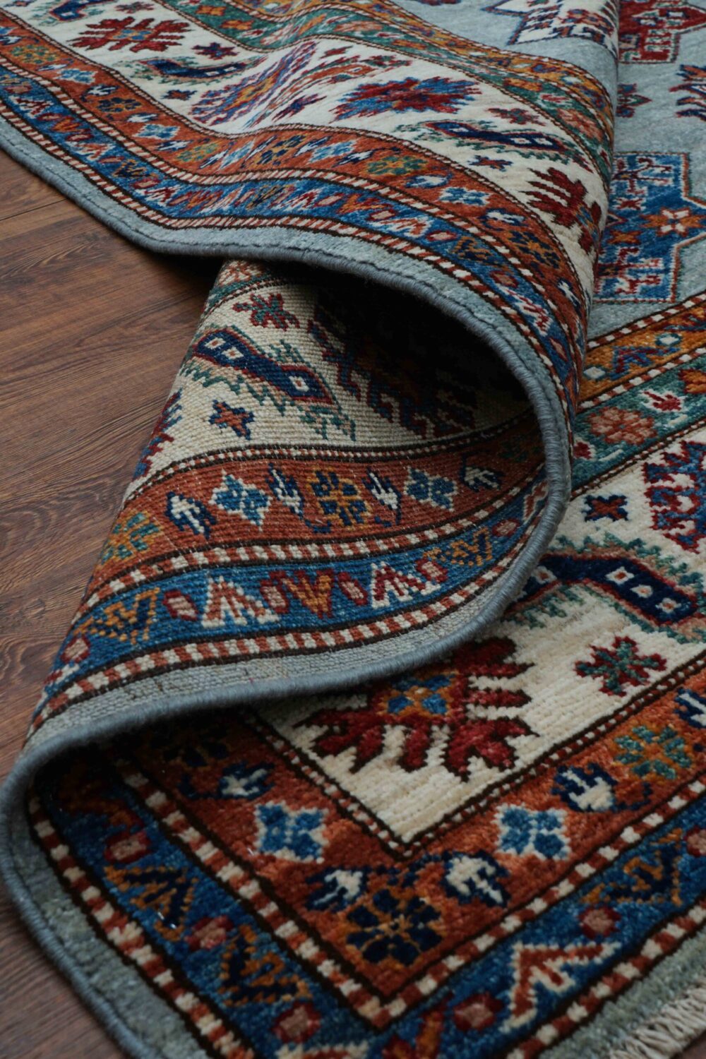 Supper kazzak 6 x 7 light blue rug adorned with red and blue geometric medallions, surrounded by intricate multicolored floral borders and patterns.