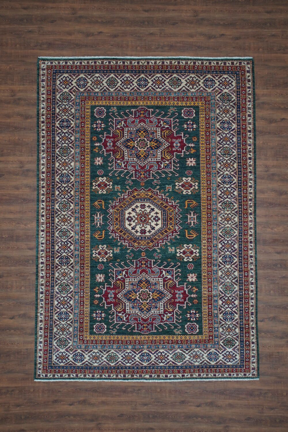 Super kazzak Luxurious 6 x 8 green rug featuring intricate red, blue, and ivory floral and geometric designs, framed by a detailed multicolored border. A timeless addition for a sophisticated and vibrant interior."