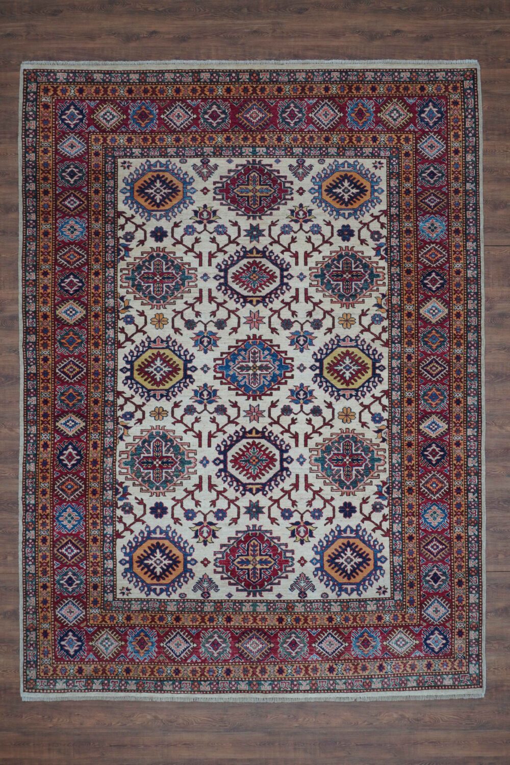 Super kazzak Handmade rug for cozy living room 6 x 8 white area rug featuring intricate octagon and floral motifs in rich red, blue, and gold hues. Highlighted by a multi-layered border with geometric patterns, this rug adds timeless elegance to any room."