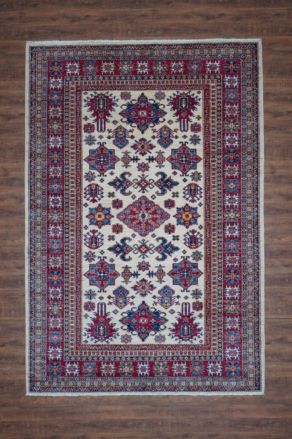 super kazzak oriental rug 6 x 8 white area rug featuring intricate octagon and floral motifs in rich red, blue, and gold hues. Highlighted by a multi-layered border with geometric patterns, this rug adds timeless elegance to any room."