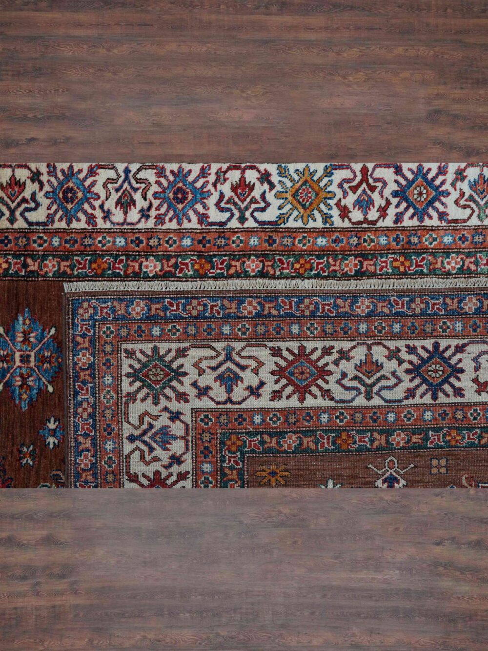 Supper kazzak 6 x 8 brown area rug showcasing geometric floral patterns in rich tones of blue, red, and ivory, bordered by intricate white accents featuring traditional motifs."