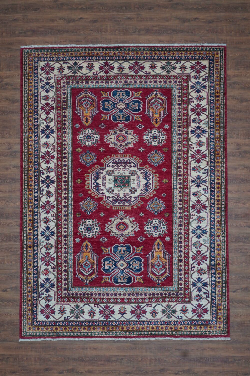 Super kazzak 6 x 8 rich red rug featuring intricate white and blue geometric medallions, surrounded by multicolored floral borders. living room rug. oriental rug