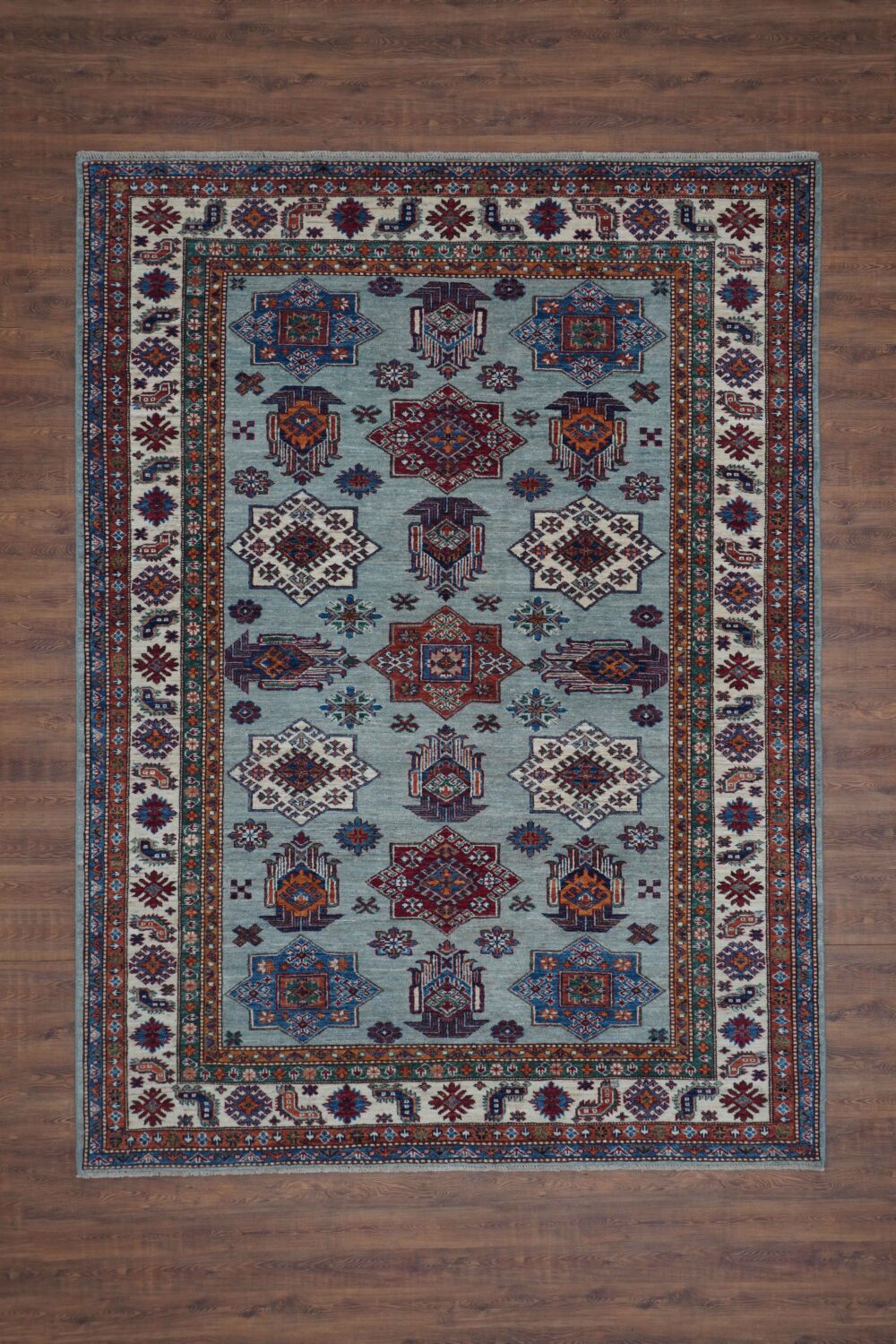 Supper kazzak 6 x 7 light blue rug adorned with red and blue geometric medallions, surrounded by intricate multicolored floral borders and patterns.