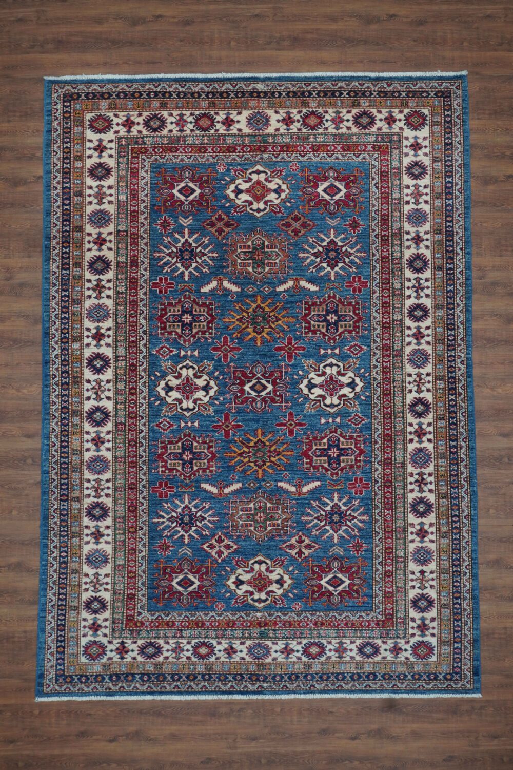 Super kazzak 7 x 8 vibrant blue and red oriental rug displayed prominently on a smooth surface, showcasing intricate patterns and textures.